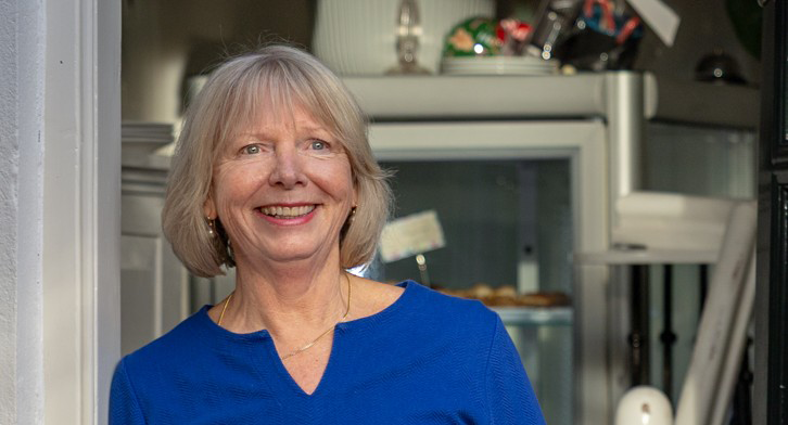 Portret van een lachende Janna van Maar voor een kast met diverse spullen.